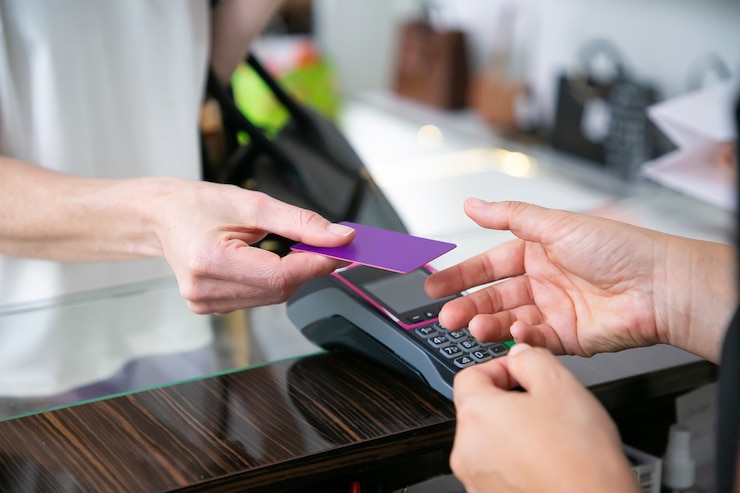 customer-giving-credit-card-cashier-desk-with-pos-terminal-payment-cropped-shot-closeup-hands-shopping-concept_74855-11658